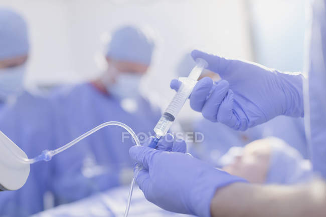 Крупним планом анестезіолога з шприц ін'єкційні анестезія медицини в Iv крапельницю в операційний зал — стокове фото