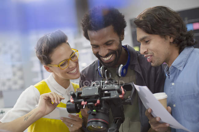 Periodistas sonrientes y camarógrafo usando cámara digital - foto de stock