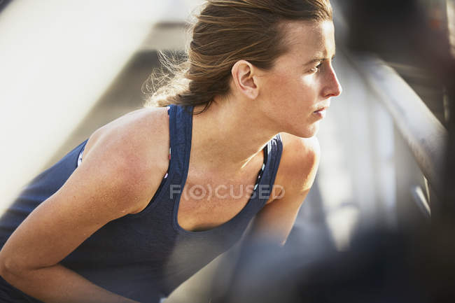 Серйозна жінка бігунка розтягується, дивлячись вбік — стокове фото