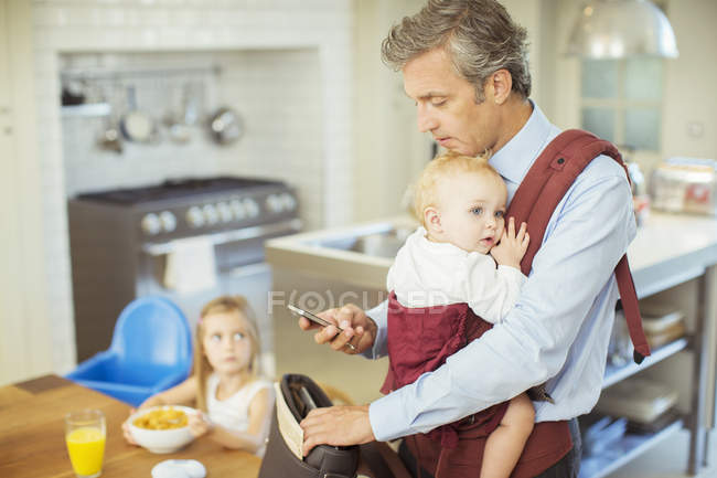 Father with baby packing bag for work — Stock Photo