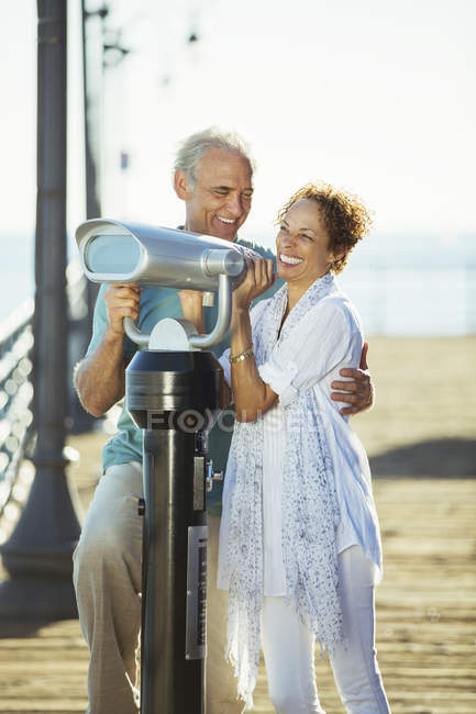 Couple using coin-operated binoculars on pier — Stock Photo