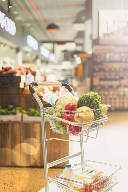 Produce and groceries in shopping cart in market — Stock Photo