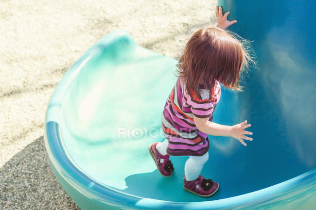 Bebé niña escalada diapositiva en el patio - foto de stock