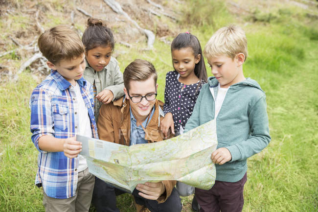 Students and teacher reading map outdoors — Stock Photo