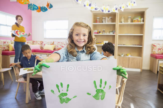 Estudiante sosteniendo pintura de dedos en clase - foto de stock