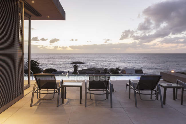 Cadeiras de lounge no pátio de luxo com vista para o mar ao pôr do sol — Fotografia de Stock