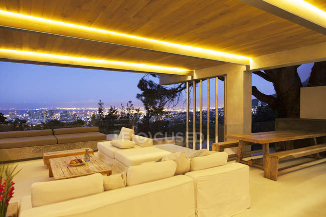 Sala de estar moderna com vista para a paisagem urbana iluminada à noite — Fotografia de Stock