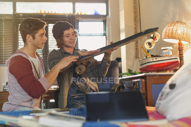 Young men friends examining skateboard — Stock Photo