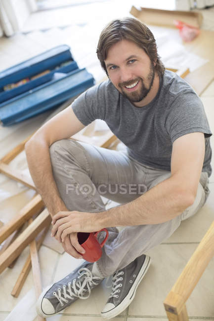 Man sitting on ground holding cup of coffee — Stock Photo