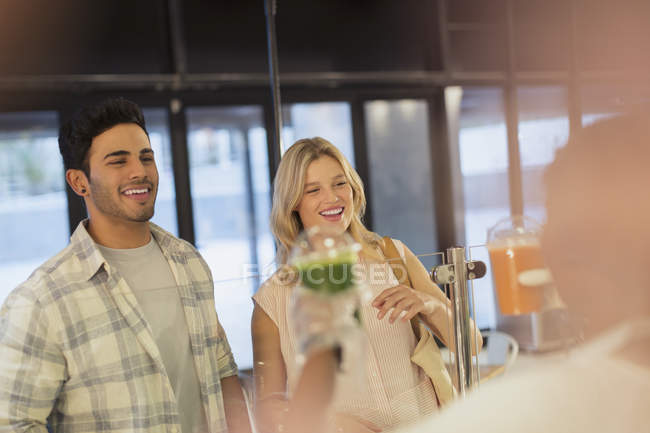 Sorridente giovane coppia riceve frullato verde da lavoratore — Foto stock