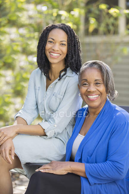 Retrato de sonriente madre e hija en el patio - foto de stock