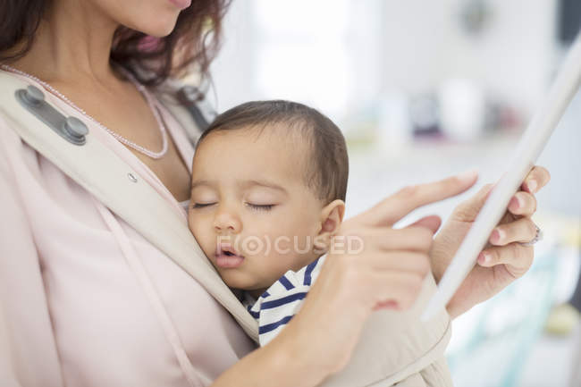 Мати зі сплячою дівчинкою за допомогою цифрового планшета — стокове фото