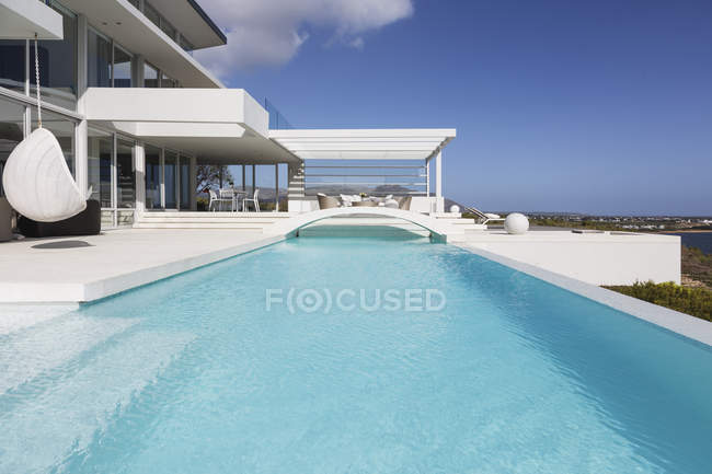 Soleado, tranquilo moderno lujoso hogar escaparate exterior piscina y patio - foto de stock