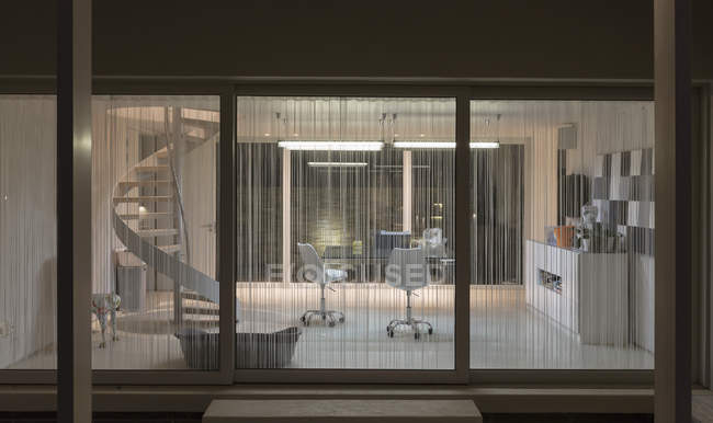 Illuminé maison moderne vitrine intérieur bureau à domicile la nuit — Photo de stock