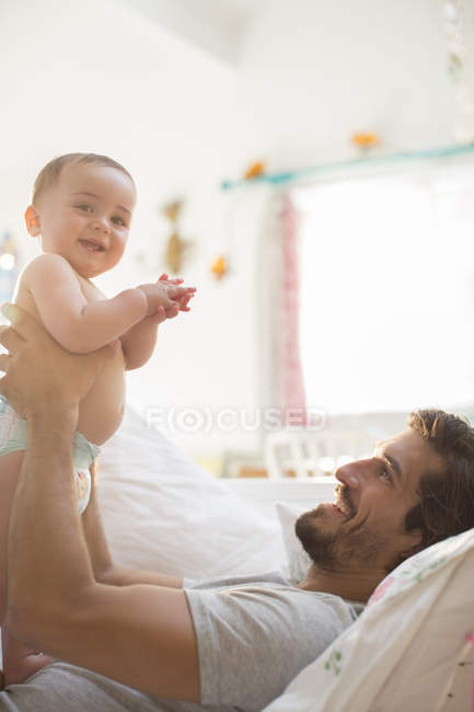 Père tenant bébé garçon sur le canapé — Photo de stock