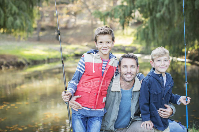 Retrato sorrindo pai e filhos com varas de pesca — Fotografia de Stock