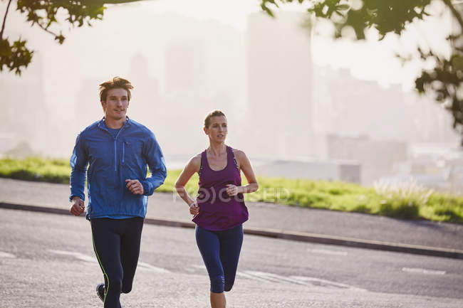Läuferpaar läuft auf sonniger Stadtstraße — Stockfoto