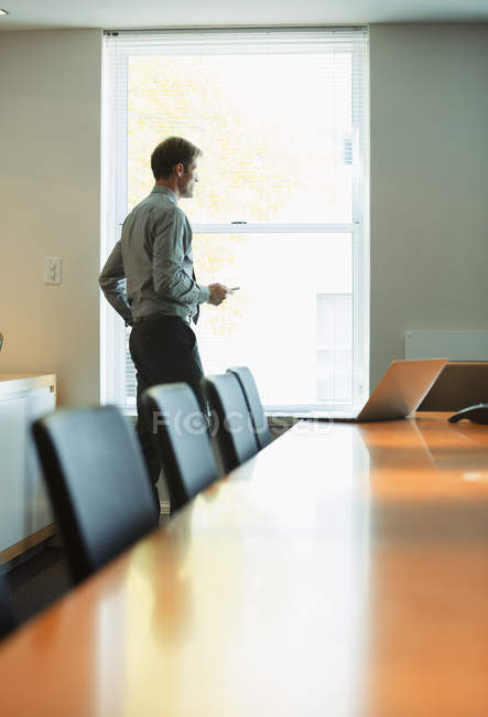 Бизнесмен стоит у окна конференц-зала — стоковое фото