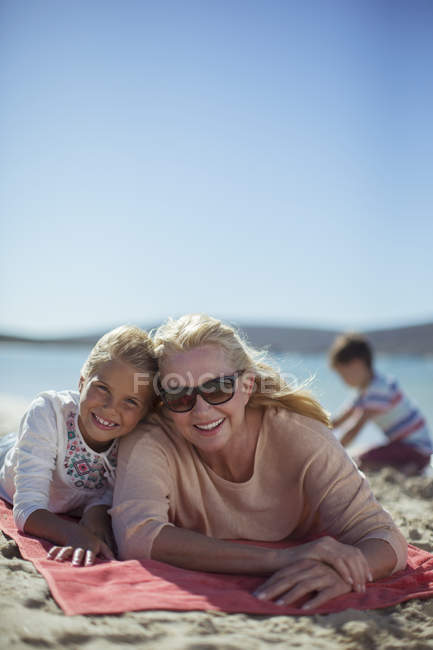 Бабуся і онука лежать на пляжному рушнику разом — стокове фото