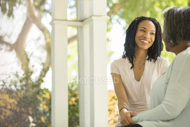 Glückliche Mutter und Tochter sprechen auf Veranda — Stockfoto