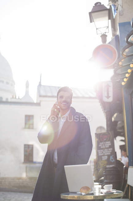 Businessman talking on cell phone at sidewalk cafe — Stock Photo