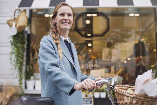 Retrato sonriente mujer con bicicleta ventana de compras - foto de stock