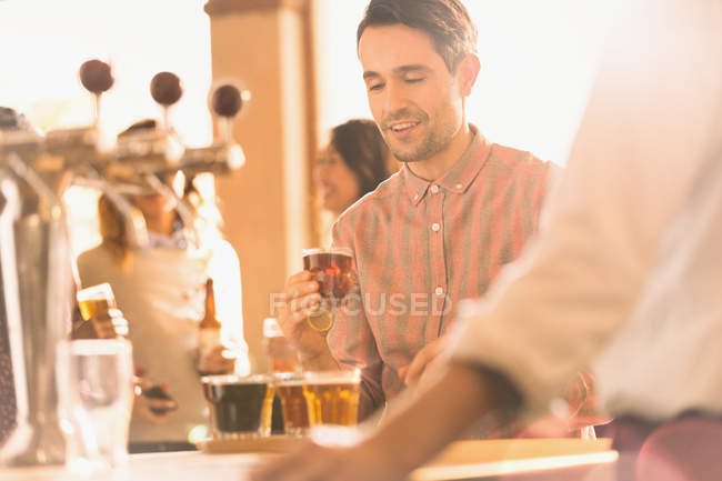Мужчина пробует пиво в баре микропивоварни — стоковое фото