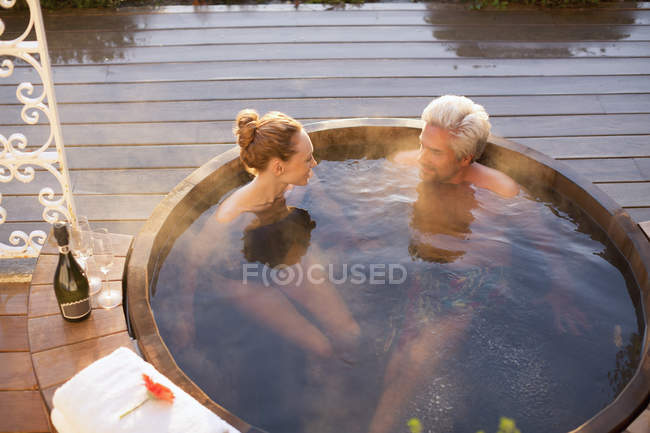 Couple trempant dans un bain à remous buvant du champagne sur le patio — Photo de stock
