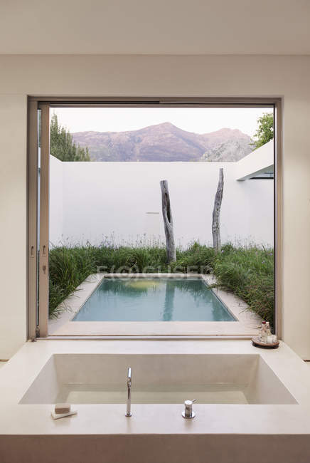 Modern bathroom overlooking swimming pool and mountains — Stock Photo