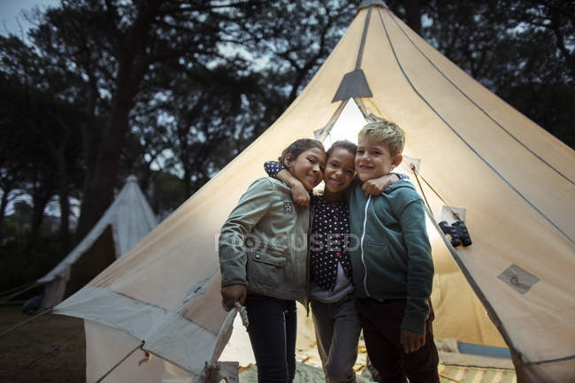 Children hugging by teepee at campsite — Stock Photo