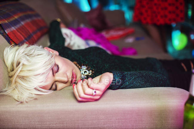 Jeune femme dormant sur le canapé à la fête — Photo de stock