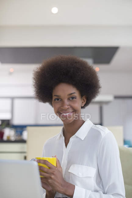 Businesswoman drinking coffee in kitchen and looking at camera — Stock Photo