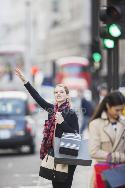 Жінка вимотує таксі на міській вулиці — стокове фото