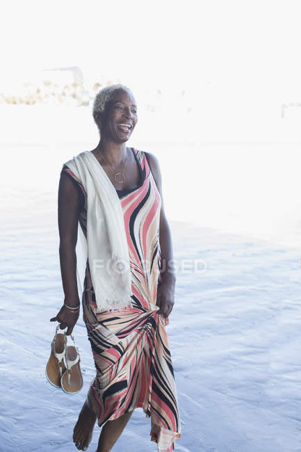 Femme noire en robe pataugeant dans l'océan — Photo de stock