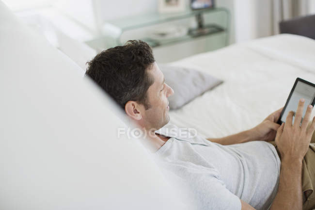 Людина за допомогою цифровий планшет на ліжку — стокове фото