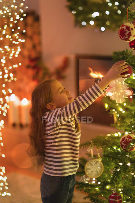 Girl hanging ornament on Christmas tree — Stock Photo