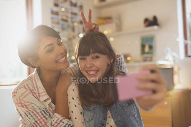 Playful young women taking selfie with camera phone — Stock Photo