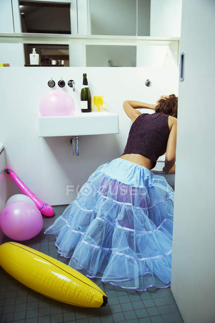 Вид сзади на женщину, блюющую в туалет на вечеринке — стоковое фото