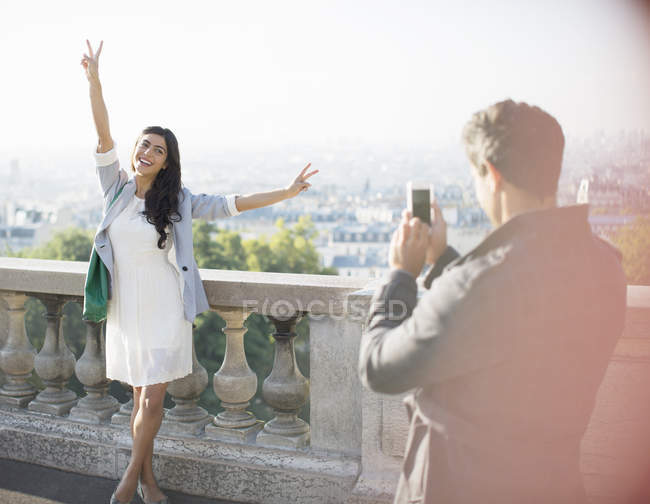 Uomo fotografare fidanzata con la città in background — Foto stock