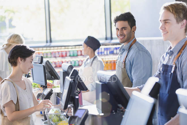 Portrait smiling, confident young male cashier working at grocery store market checkout — Stock Photo