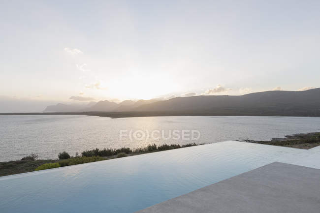 Tranquil sunset beyond infinity pool and ocean — Stock Photo
