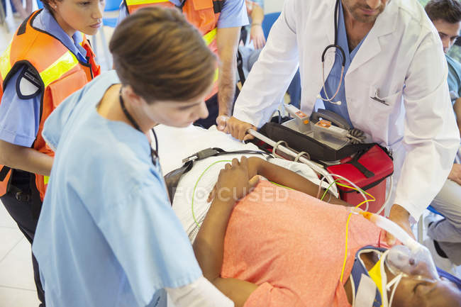 Médecin, infirmière et ambulancier examinant le patient sur civière — Photo de stock