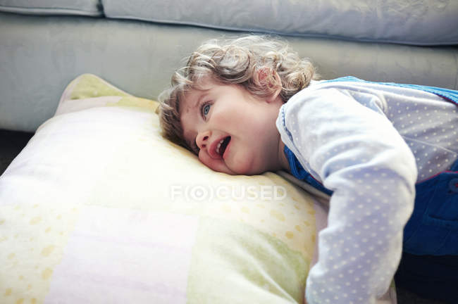 Mädchen liegt auf Kissen im Wohnzimmer — Stockfoto