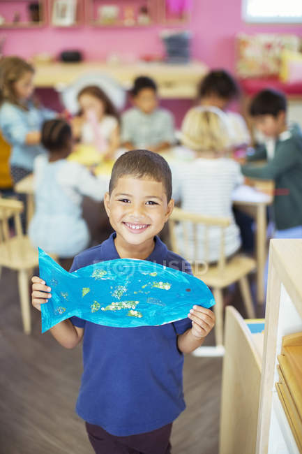 Étudiant tenant des poissons peints en classe — Photo de stock