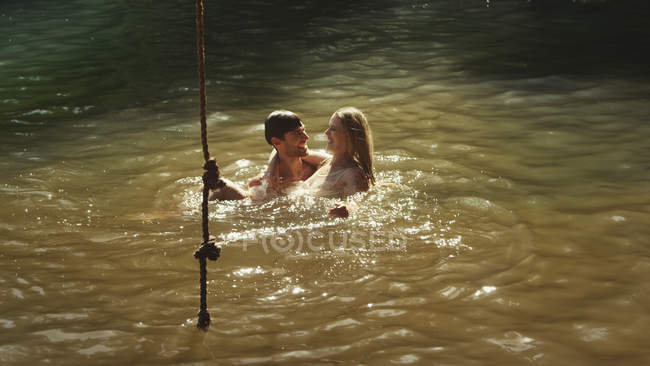 Casal jovem nadando em lago ensolarado — Fotografia de Stock