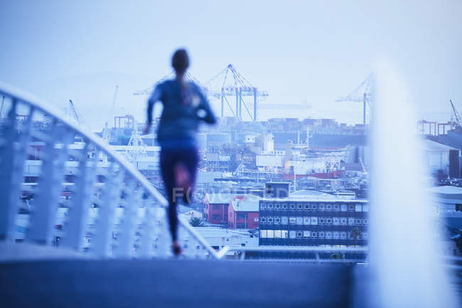 Жінка біжить на міському пішохідному мосту на світанку — стокове фото