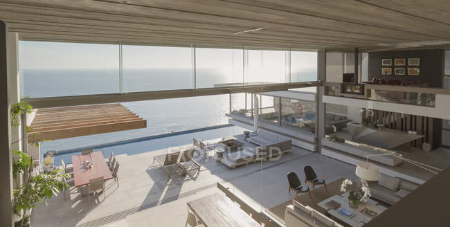 Вид з висоти сучасний, розкішний будинок вітрина інтер'єру вітальні та патіо з сонячним видом на океан — стокове фото