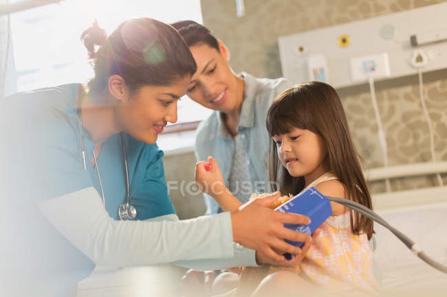 Female nurse helping girl patient in hospital room — Stock Photo