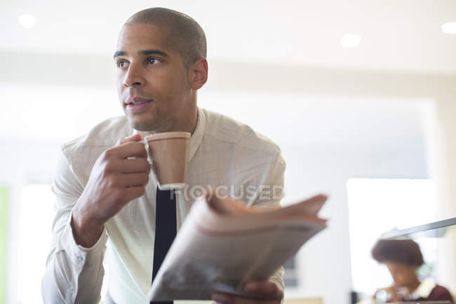 Uomo d'affari che legge giornali e beve caffè a casa — Foto stock