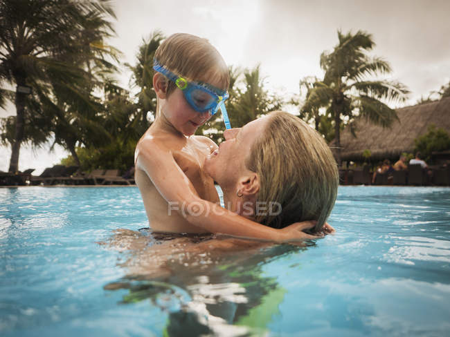 Mãe e filho abraçando na piscina — Fotografia de Stock
